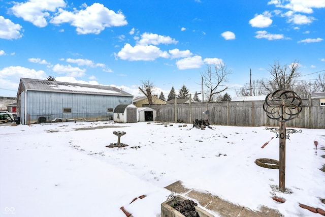 snowy yard featuring a storage unit