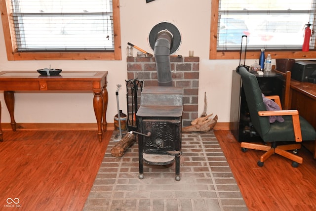 office space featuring a wealth of natural light, a wood stove, and wood-type flooring