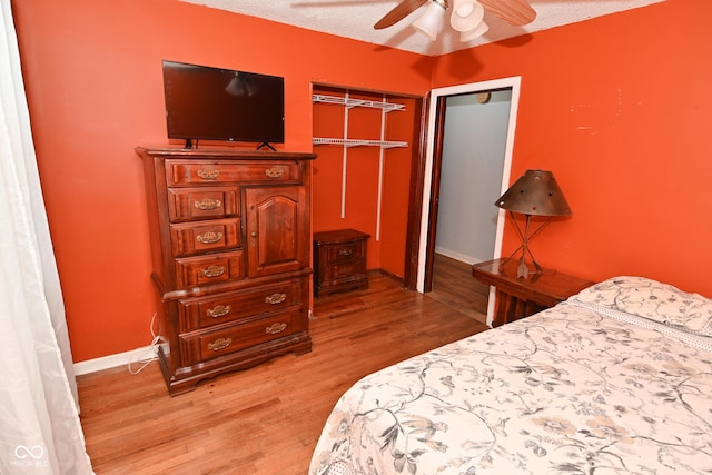 bedroom with ceiling fan, wood-type flooring, a closet, and a textured ceiling