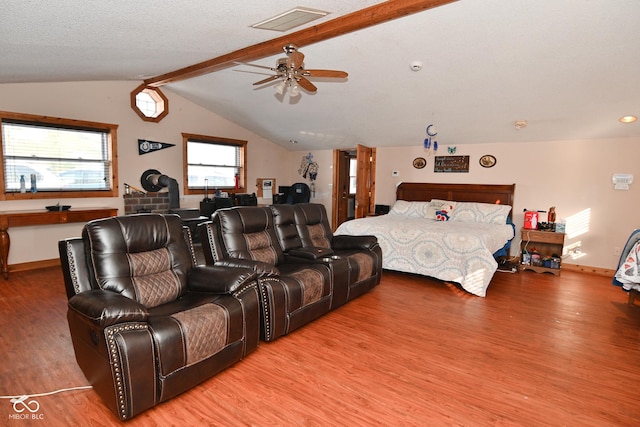 bedroom with ceiling fan, vaulted ceiling with beams, a textured ceiling, and hardwood / wood-style flooring