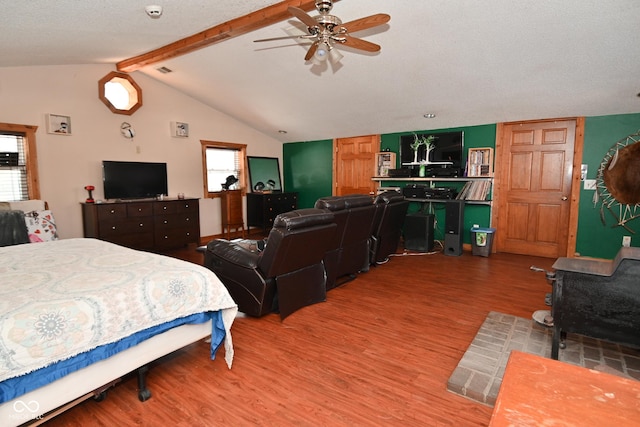 bedroom featuring a textured ceiling, ceiling fan, hardwood / wood-style floors, and vaulted ceiling with beams