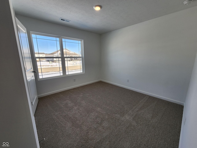 spare room featuring carpet floors, visible vents, a textured ceiling, and baseboards