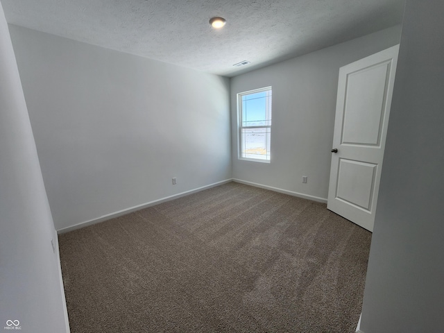 unfurnished room with a textured ceiling, carpet, visible vents, and baseboards