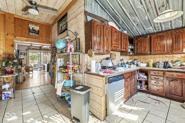 kitchen with light tile patterned floors, stainless steel dishwasher, vaulted ceiling with beams, and wood walls