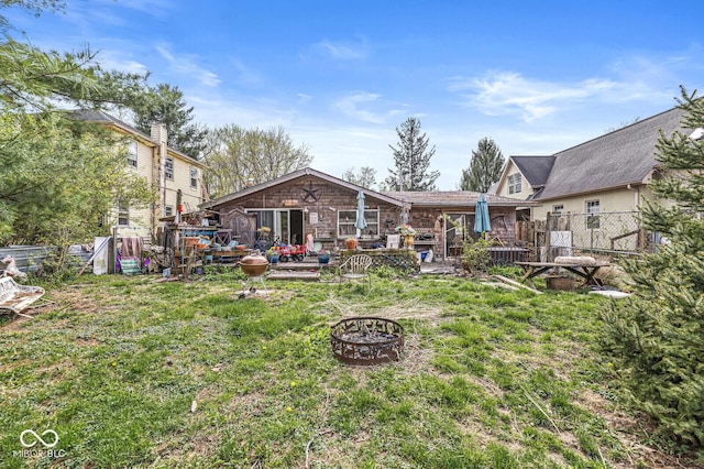 back of house featuring a yard, a wooden deck, fence, and a fire pit
