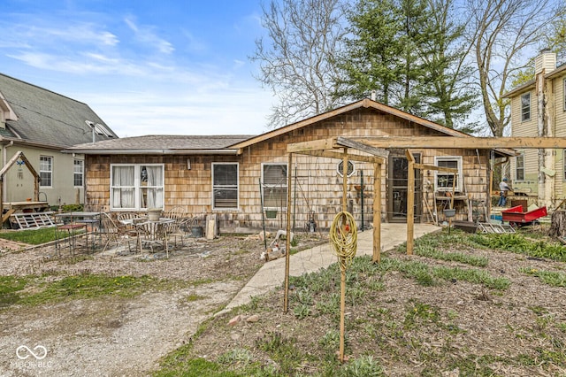 back of property with a shingled roof and a patio area