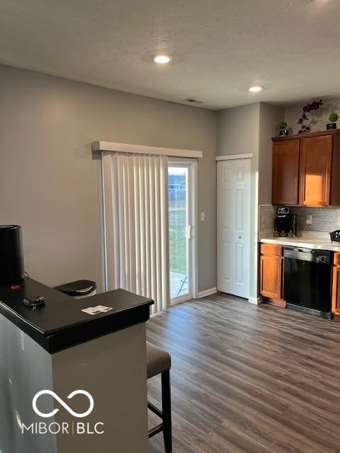 kitchen with a breakfast bar area, black dishwasher, dark hardwood / wood-style flooring, and tasteful backsplash