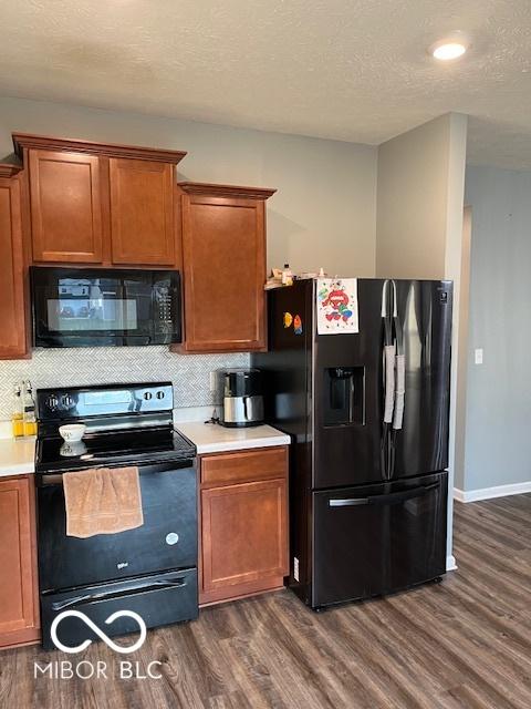 kitchen with a textured ceiling, dark hardwood / wood-style flooring, tasteful backsplash, and black appliances