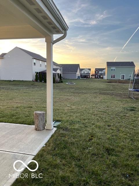 yard at dusk featuring a patio area and a trampoline