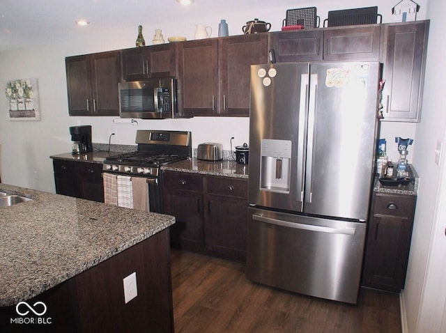 kitchen featuring dark wood-type flooring, sink, dark brown cabinets, stainless steel appliances, and light stone countertops