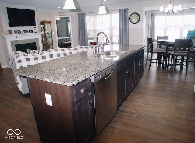 kitchen with stainless steel dishwasher, sink, hanging light fixtures, and a center island with sink