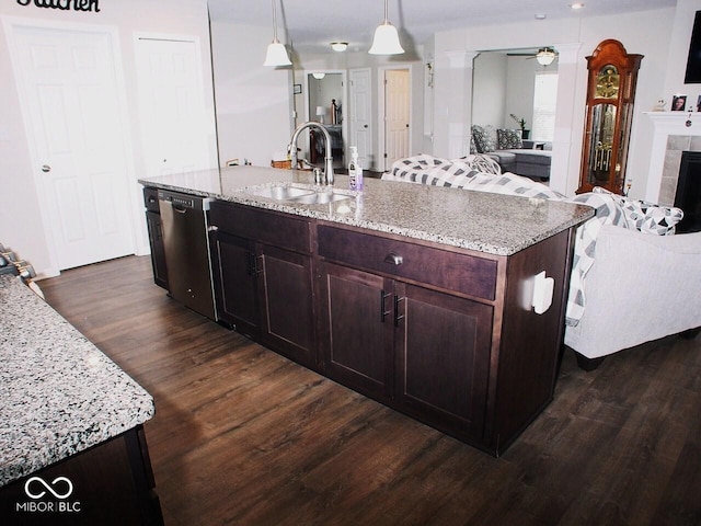 kitchen featuring dark hardwood / wood-style floors, decorative light fixtures, dishwasher, sink, and a kitchen island with sink