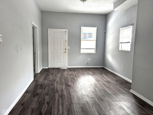 unfurnished room with dark wood-type flooring, plenty of natural light, and a textured ceiling