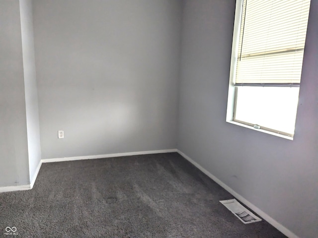 spare room with dark colored carpet