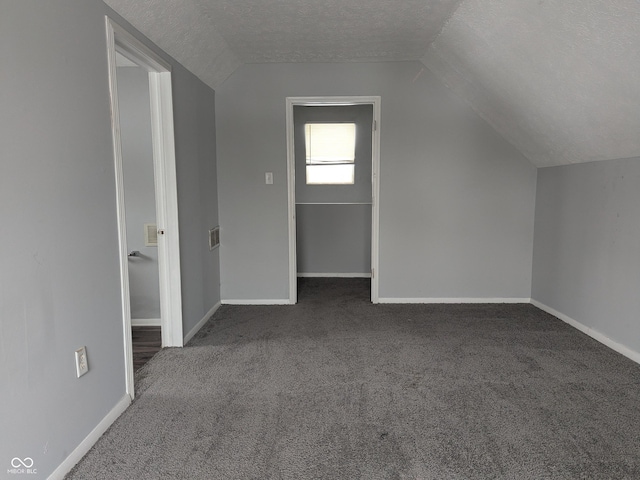 bonus room featuring dark carpet, a textured ceiling, and lofted ceiling