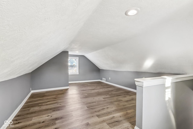 bonus room with vaulted ceiling, dark hardwood / wood-style floors, and a textured ceiling