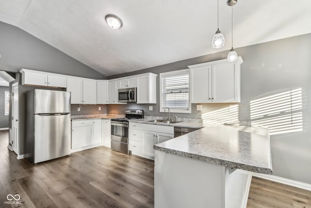 kitchen featuring sink, appliances with stainless steel finishes, hanging light fixtures, white cabinets, and vaulted ceiling