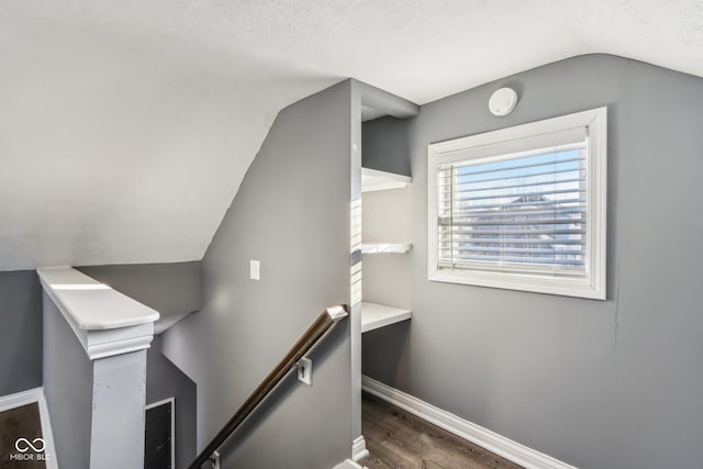 stairs featuring wood-type flooring, vaulted ceiling, and a textured ceiling