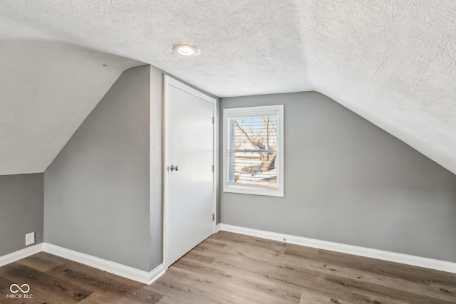 bonus room with hardwood / wood-style flooring, vaulted ceiling, and a textured ceiling