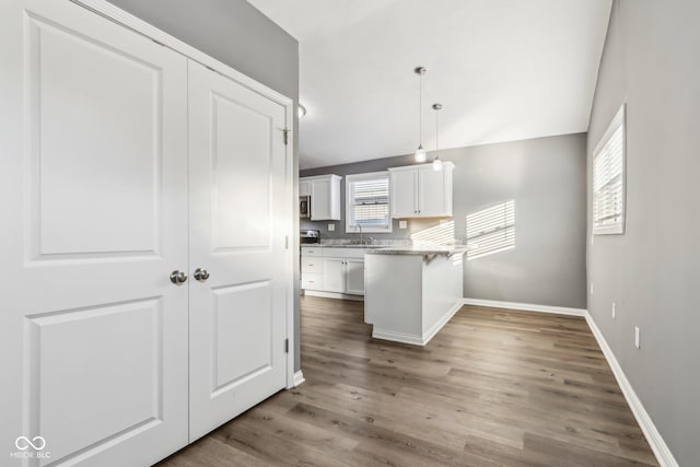 kitchen with white cabinetry, sink, hardwood / wood-style floors, and decorative light fixtures