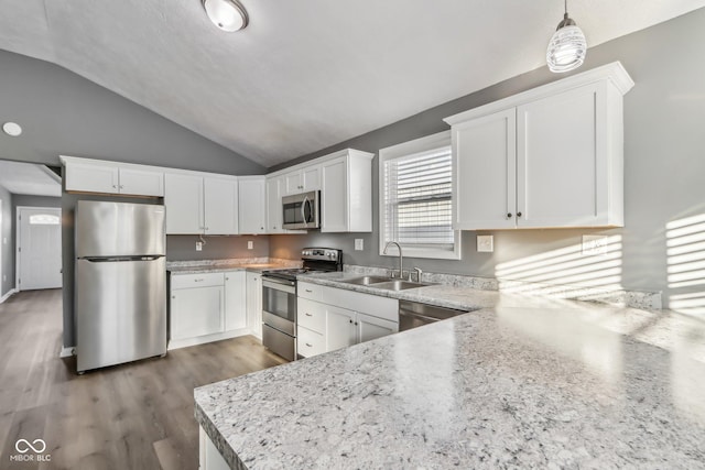 kitchen featuring sink, appliances with stainless steel finishes, white cabinets, decorative light fixtures, and vaulted ceiling