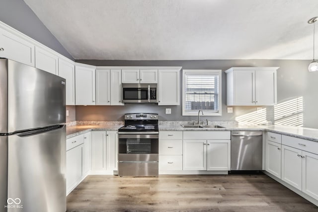 kitchen featuring white cabinetry, sink, vaulted ceiling, and appliances with stainless steel finishes