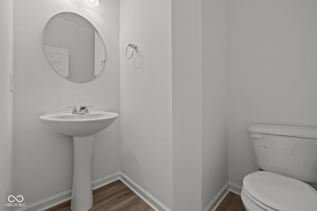 bathroom featuring toilet, baseboards, and wood finished floors