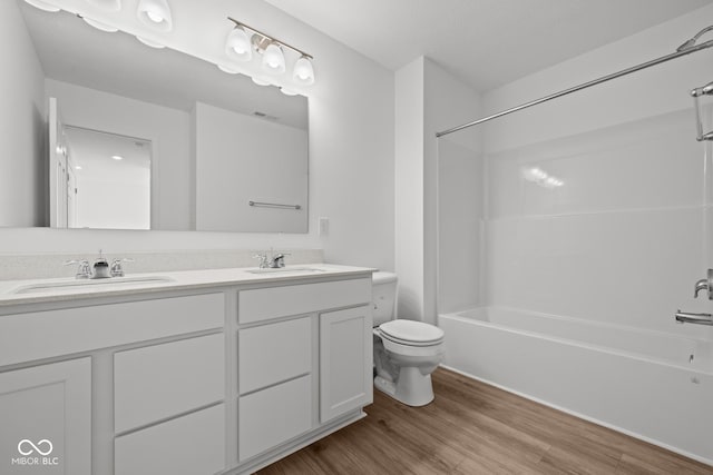 bathroom featuring shower / tub combination, toilet, wood finished floors, and a sink