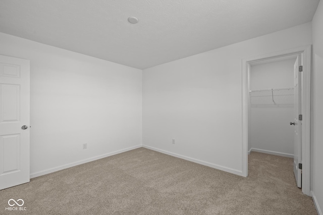 unfurnished bedroom featuring a closet, baseboards, carpet, and a spacious closet