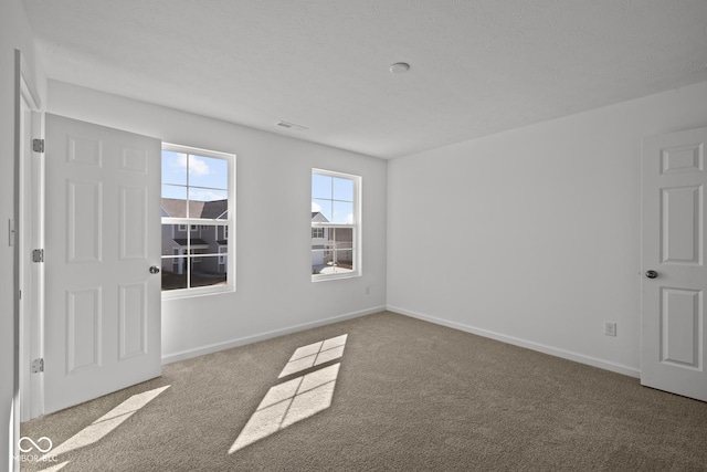 carpeted spare room with visible vents and baseboards