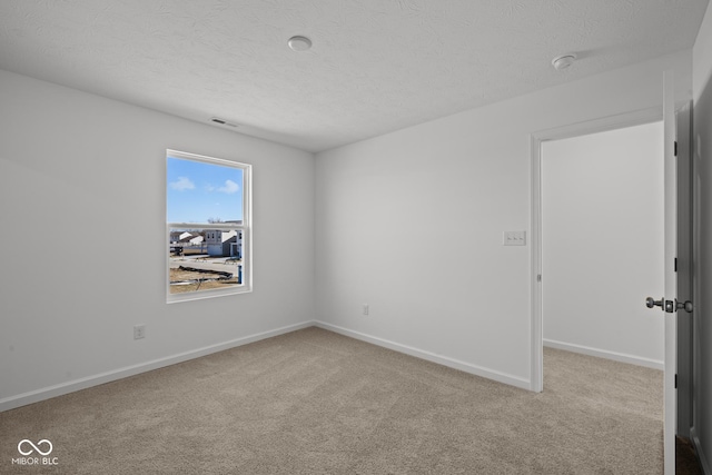 carpeted empty room featuring visible vents, a textured ceiling, and baseboards