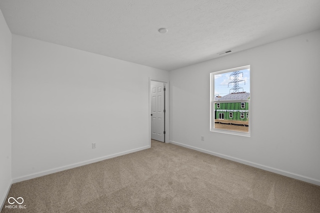 spare room featuring baseboards, visible vents, carpet floors, and a textured ceiling