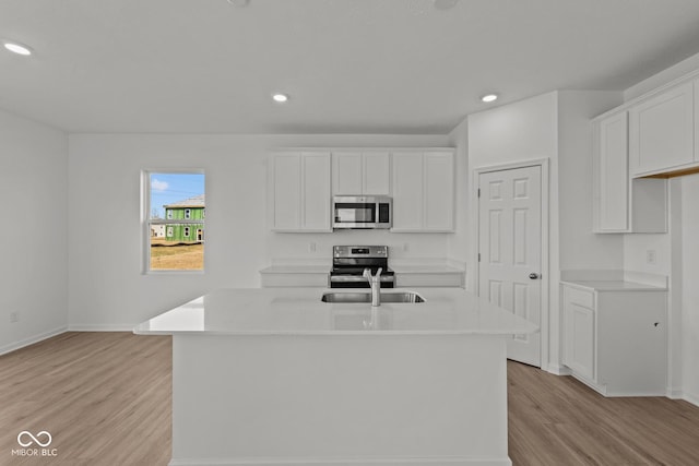 kitchen featuring light wood-style flooring, stainless steel appliances, light countertops, and a sink