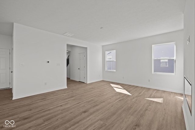 spare room with a wealth of natural light, baseboards, and wood finished floors