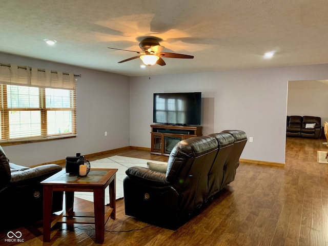 living room featuring ceiling fan, light hardwood / wood-style floors, and a textured ceiling