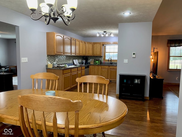 dining room featuring a chandelier, a wealth of natural light, a textured ceiling, and dark hardwood / wood-style flooring