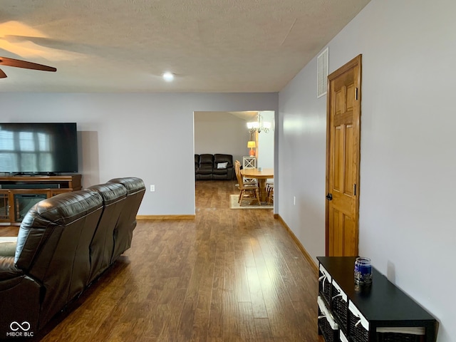 living room with wood-type flooring, ceiling fan with notable chandelier, and a textured ceiling