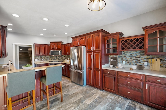 kitchen with tasteful backsplash, appliances with stainless steel finishes, a kitchen bar, and light wood-type flooring