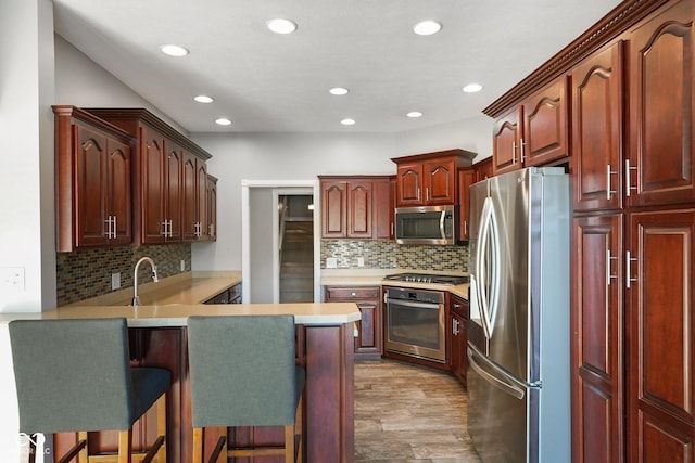 kitchen featuring backsplash, a kitchen breakfast bar, kitchen peninsula, stainless steel appliances, and light hardwood / wood-style flooring