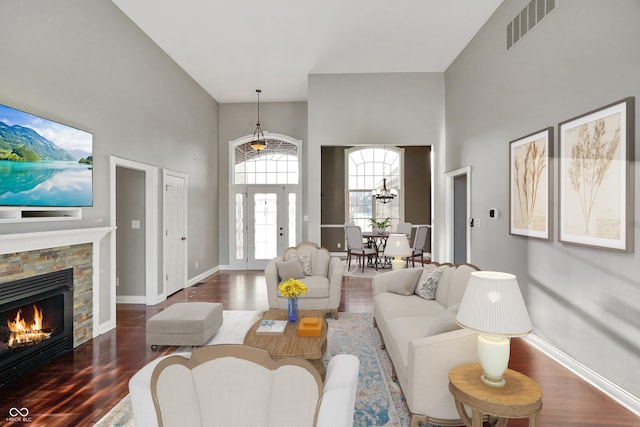 living room featuring a high ceiling, wood-type flooring, and a stone fireplace