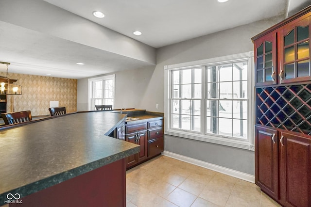 kitchen featuring sink, light tile patterned floors, an inviting chandelier, a kitchen bar, and decorative light fixtures