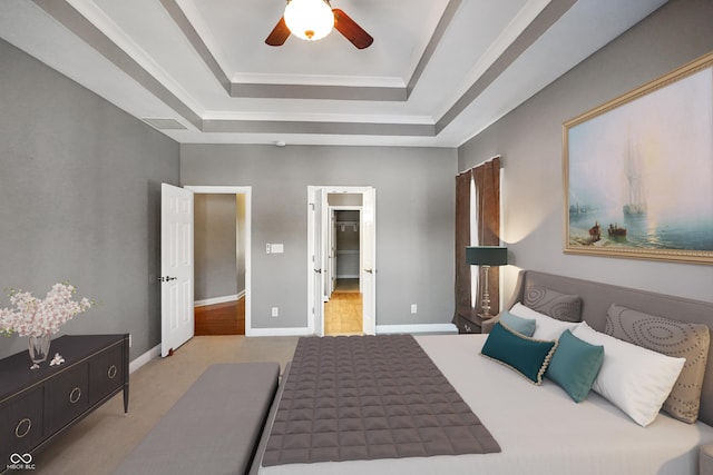 carpeted bedroom with a tray ceiling and ceiling fan