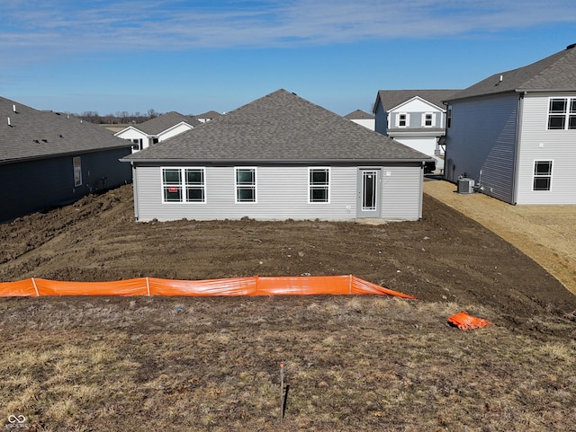 rear view of house with central AC and a lawn