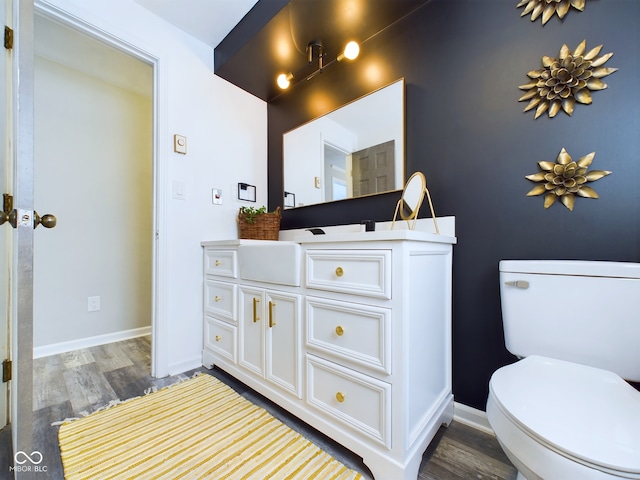 bathroom with wood-type flooring, toilet, and vanity