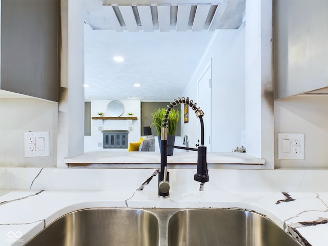 details featuring light stone counters, sink, and a large fireplace