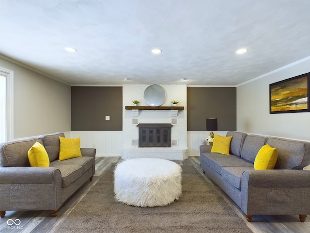 living room featuring a brick fireplace, ornamental molding, and dark hardwood / wood-style flooring