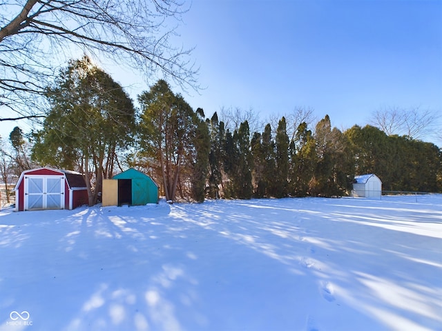 snowy yard featuring a storage shed