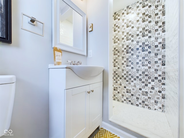 bathroom featuring vanity, toilet, walk in shower, and tasteful backsplash