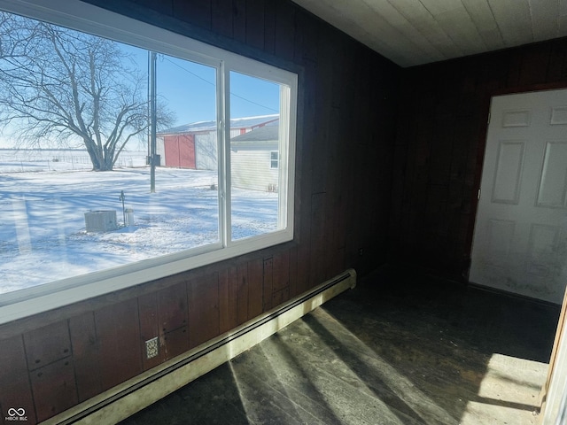 interior space with a baseboard heating unit and wood walls