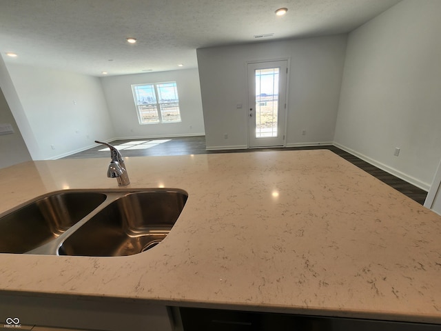 interior space featuring baseboards, a sink, and light stone countertops